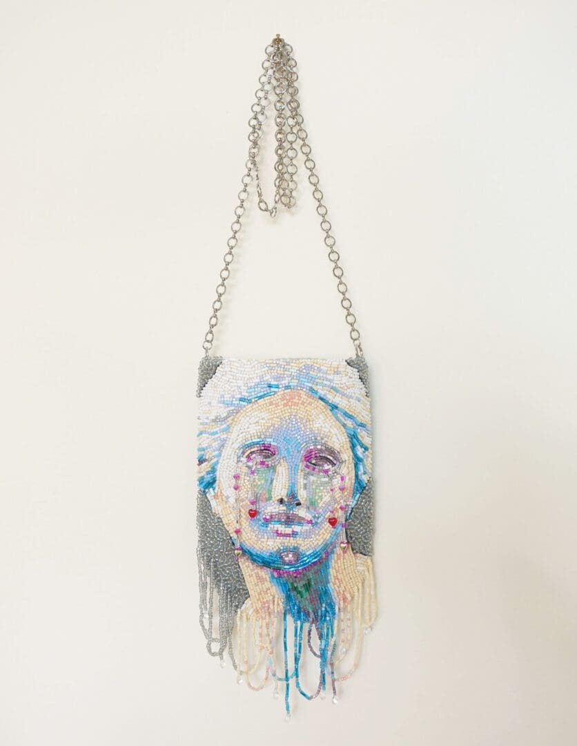 venus purse handing on a white wall with a face on it.