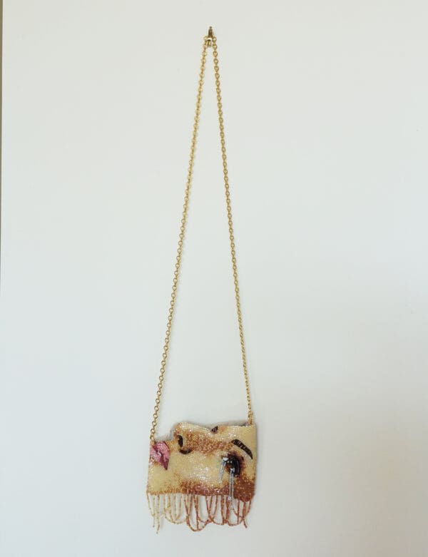 Beaded purse with gold chain and face design.