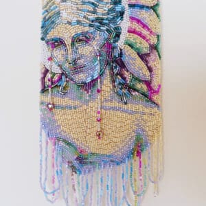 Beaded handbag featuring a detailed, colorful portrait of a Angel with flowing hair and fringe details hanging from the bottom.